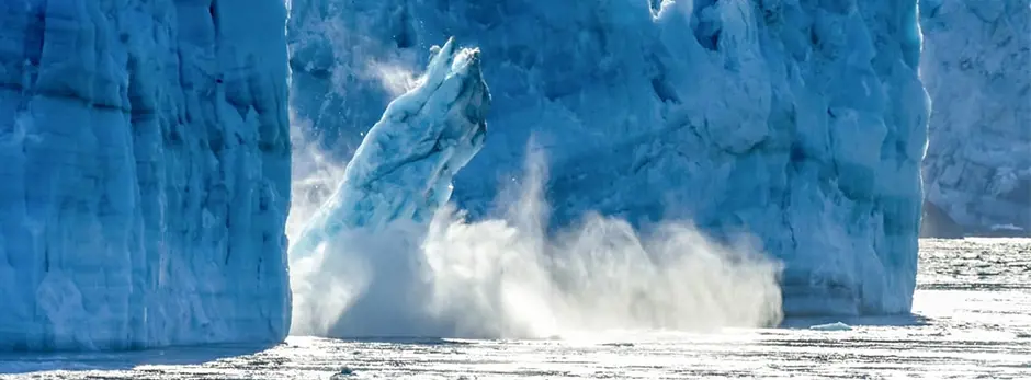 Part of an iceberg breaks off from larger piece.